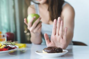 Woman choosing to eat an apple rather than sugary food