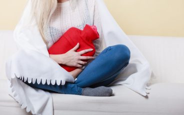 Woman holding a hot-water bottle to her stomach due to cramping